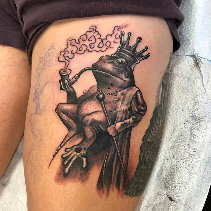 Fine line black and grey upper thigh tattoo of the smoking frog king by tattoo artist Russ Howie of Sacred Mandala Studio in Durham, NC.